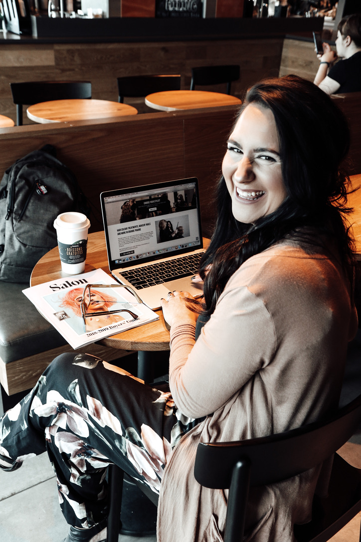 Danielle smiling in a cafe in front of her laptop
